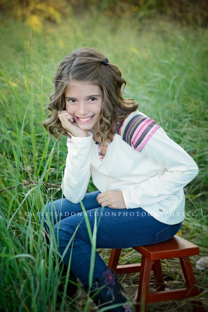 girl posing on stool in field of tall grass, Arizona