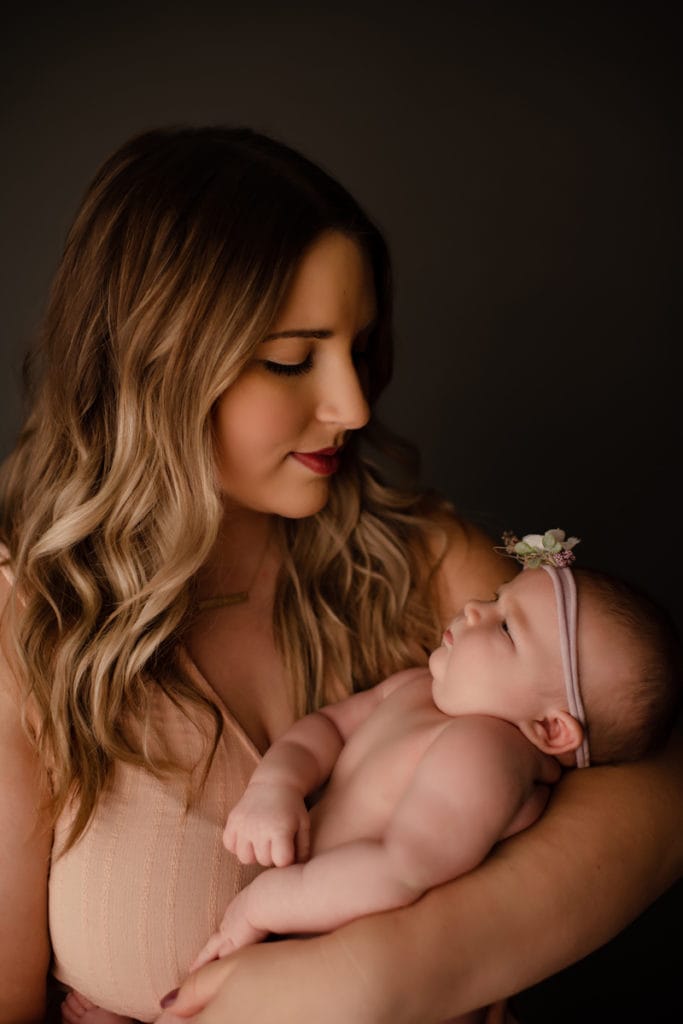 Newborn Photographer, a mother holds her baby admiring her